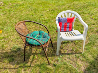 Two outdoor chairs with colorful cushions arranged on grass lawn creating comfortable garden...