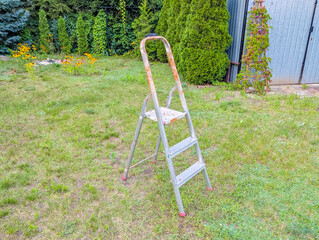 Yellow stepladder positioned on green lawn ready for outdoor maintenance work in residential garden