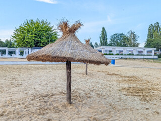 Single thatched beach umbrella standing alone on empty sandy beach landscape