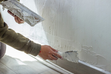 Construction worker applying plaster on wall with spatula