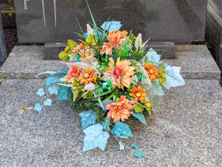 Warsaw, Poland, June 16, 2025 Vibrant floral bouquet arrangement rests on weathered stone grave...