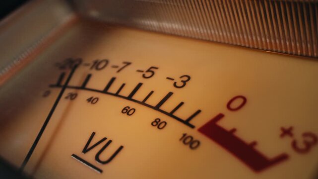 Analog dial indicator of audio signal level amplifier. Vintage arrow moves with sound level. Round classic volume indicator with yellow backlight, VU meters. Close-up of old measuring dB decibels
