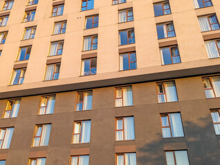 Low angle view of modern orange brick residential building with blue windows against clear sky