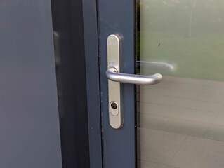 Close-up detail of modern door handle and lock mechanism on dark wooden door surface