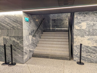 Concrete staircase with metal handrails in industrial basement setting with natural lighting from...