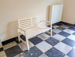 White heating radiator mounted on wall above black and white checkered marble floor in elegant...