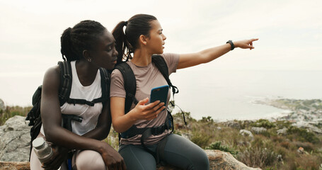 Girl, friends and hiking with phone on mountain, talk or point with digital map on trail. Women,...