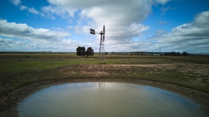 Rural landscape with windmill and pond.