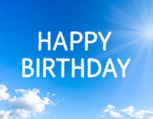Happy Birthday written in fluffy white clouds against a bright blue sky