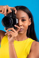 Young photographer taking photos with vintage camera on blue background