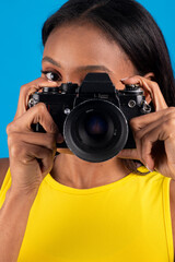 Young photographer taking photos with vintage camera on blue background