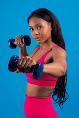 Young black woman lifting weights on blue background