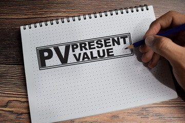 Concept of PV - Present value write on book isolated on Wooden Table.