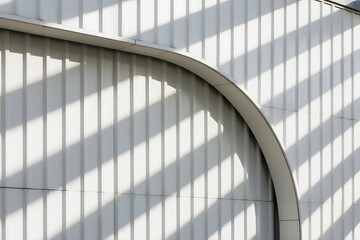 A modern architectural facade features a curved structure with vertical light strips casting distinct shadows.