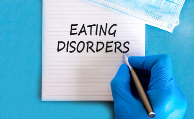 Eating disorders symbol. Concept words Eating disorders on beautiful white note. Doctor's hand in...