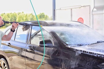 A man washes his car at a self-service station.