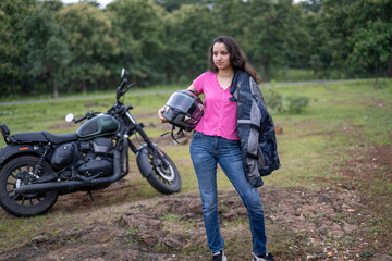Fototapeta premium Strong independent Indian woman biker: beautiful girl, stylish rider, motorcycle adventure, elegant jacket, confident posture, powerful machine, free spirit, road journey, fearless attitude.