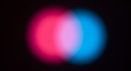 Two overlapping blurred circles of pink and blue light on a black background image photo