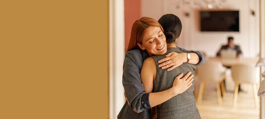 Professional woman embracing colleague showing empathy and teamwork while working in corporate office