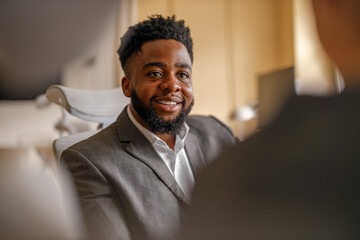 Portrait of confident businessman smiling and looking at coworker while working in corporate office