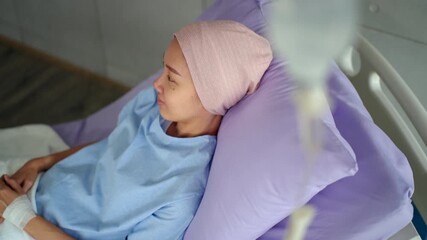 Asian patient woman with cancer smiling while resting on bed with positive
emotion and looking out the window after chemotherapy at hospital, cancer female feeling calm and positive hope thinking.
