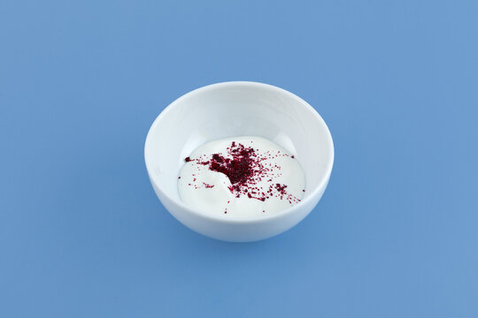 Red fat-soluble dye particles dissolves in buttercream. Azorubine or Carmoisine powder on cream surface. Oil-phase mixture. Controversial food additives. E122, colorant