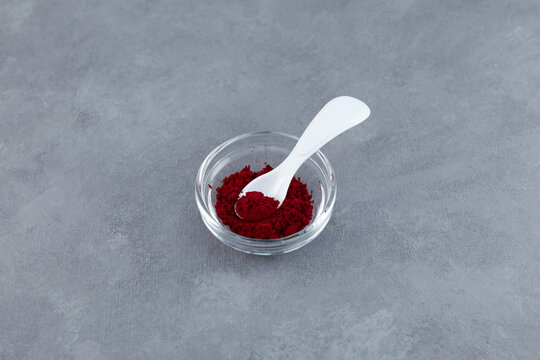 Powder of Allura Red AC, also known as FD&C Red 40 in glass bowl. Food additive E129, azo dye commonly used in cosmetics, drugs, and food. Controversial additives. Hyperactivity in children problems