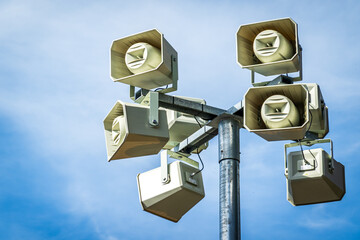 Alert system speakers mounted on tall pole against clear blue sky during daytime enhance safety in...