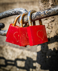 Padlock with heart symbol hanging on a wire fence against a clear blue sky in a serene outdoor...