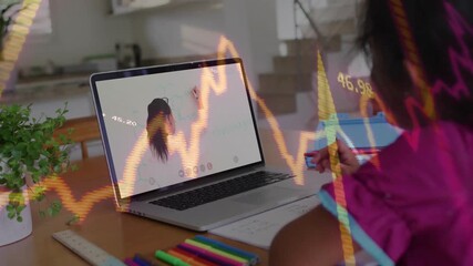 Girl joining finance lesson on laptop and taking notes learning from translucent chart overlays - Powered by Adobe