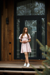 The girl is standing on a wooden veranda in front of a large black doorway with windows.