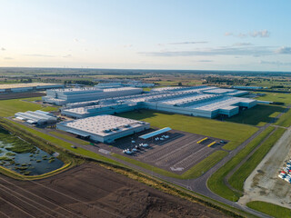 Aerial view of a car manufacturing plant at sunset, producing combustion and electric cars.