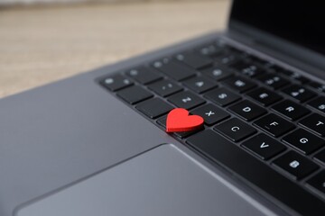 Online dating site. Red heart and laptop on table, closeup