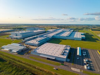 Aerial view of a car manufacturing plant at sunset, producing combustion and electric cars.