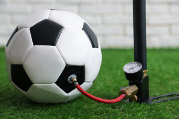 Soccer ball and manual air pump indoors, closeup