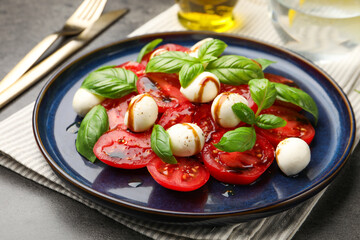 Tasty salad Caprese served with balsamic vinegar on grey table, closeup
