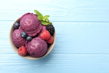Delicious sorbet with fresh berries and mint in bowl on light blue wooden table, top view. Space for text