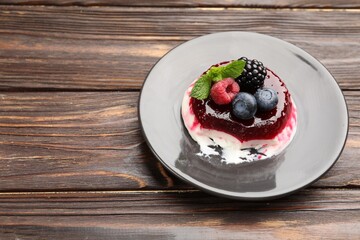 Delicious panna cotta with berries, jam and mint on wooden table, closeup. Space for text