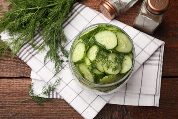 Making pickles. Slices of fresh cucumbers in open jar, dill and spices on wooden table, flat lay