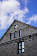 Historical brick building with unique architecture under a cloudy sky in a serene setting