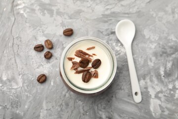 Delicious panna cotta with chocolate chunks and coffee beans on grey textured table, flat lay