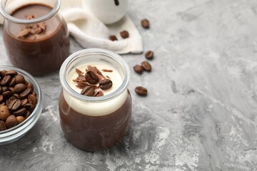 Delicious panna cotta with chocolate chunks and coffee beans on grey textured table. Space for text