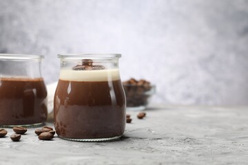 Delicious panna cotta and coffee beans on grey textured table, closeup. Space for text