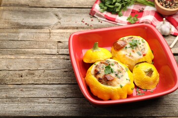 Tasty stuffed pattypan squashes in baking dish on wooden table, closeup. Space for text
