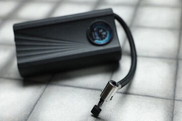 One modern tire inflator on light tiled background, closeup