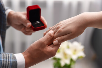 Man with engagement ring making marriage proposal to his girlfriend indoors, closeup