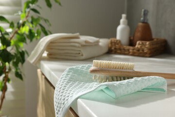 Clean waffle towels, brush and cosmetic products on counter in bathroom, selective focus
