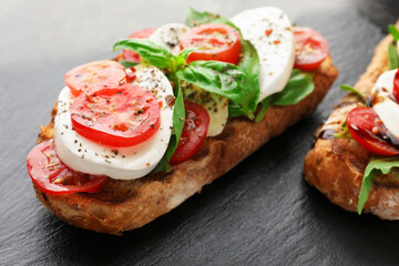 Delicious sandwiches with mozzarella cheese, tomatoes and basil on table, closeup