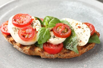 Delicious sandwich with mozzarella cheese, tomato and basil on plate, closeup