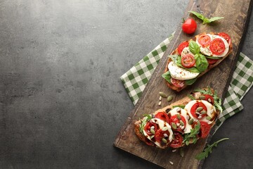 Delicious sandwiches with mozzarella cheese and tomatoes on grey table, top view. Space for text